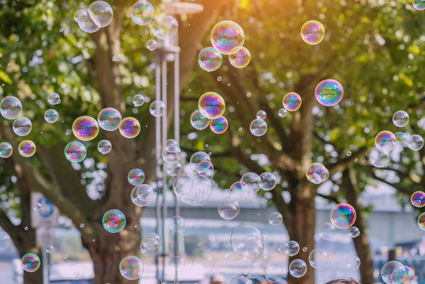 Many soap bubbles in city park. Children, happiness and fun concept - Photo, Image