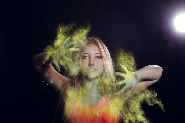 Chica con polvo de color explotando a su alrededor y en el fondo
. - Foto, Imagen
