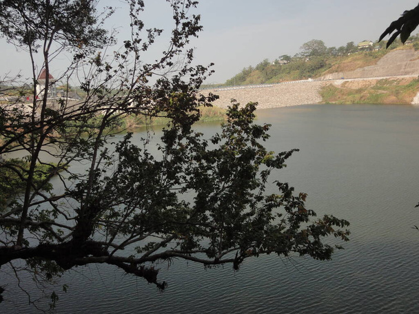 het wateroppervlak van het reservoir, gezien van achter de struiken en bomen. het wateroppervlak heeft kleine rimpelingen - Foto, afbeelding