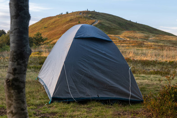 芝生の上の灰色のテントは夕日の山を見下ろす。高品質の写真 - 写真・画像
