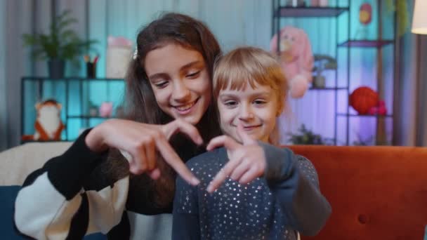 I love you. Smiling teenage child little sister kid girls makes heart gesture demonstrates love sign, good feelings, sympathy. Siblings children best friends at home. Friendship family relationship - Footage, Video