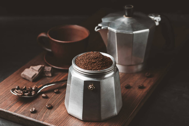 Moka kahvipannu täynnä ruskeaa jauhettua kahvia tummalla puulevyllä, valmistaudu panimoon italialainen espresso. - Valokuva, kuva