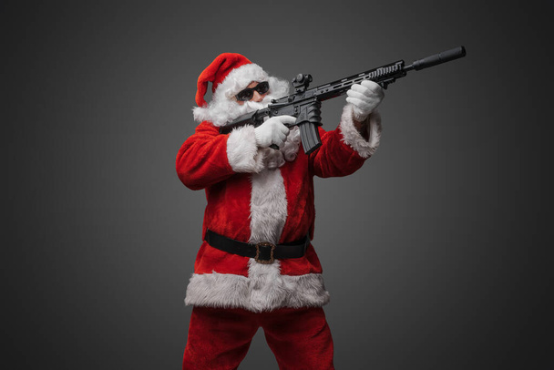 Studio shot van de kerstman schutter met lange baard richten geweer. - Foto, afbeelding