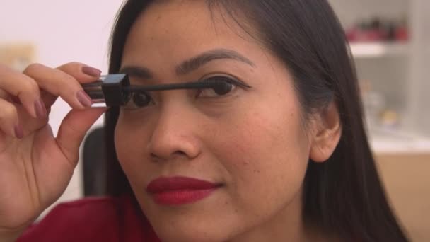CLOSE UP: Nahaufnahme einer hübschen philippinischen Dame, die Mascara-Pinsel für Wimpern benutzt. Kopfschuss einer jungen Frau, die Augen aufsetzt, für besondere Anlässe geschminkt. Weibliche Person kümmert sich um ihren glamourösen Look. - Filmmaterial, Video