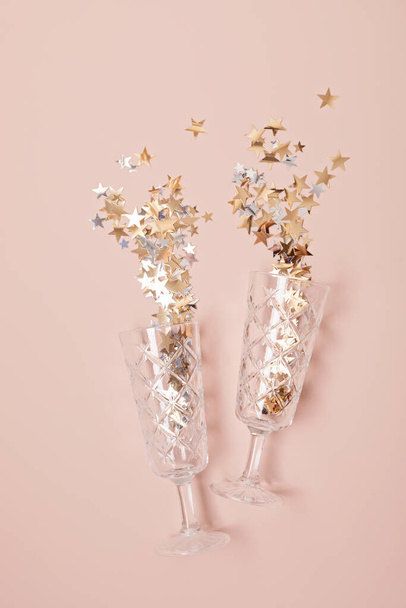 Шампанское или игристые бокалы вина с конфетти на розовом фоне. Идея празднования Рождества, Нового года, дня рождения или свадьбы. Вид сверху, плоский, копировальное пространство - Фото, изображение