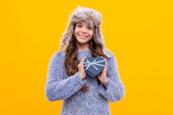 positive teen girl wear earflap hat with purchase ox on yellow background, valentines day. - Photo, Image