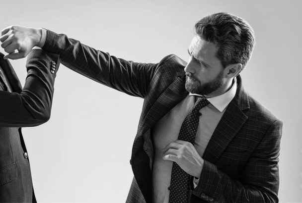 Агрессивный профессиональный человек бизнесмен бьет коллегу с кулаком серого фона, драка. - Фото, изображение