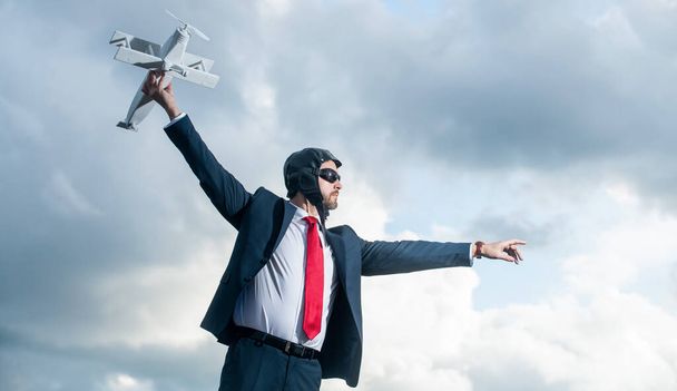 スーツ姿のビジネスマンが空を背景に飛行機のおもちゃを発射. - 写真・画像