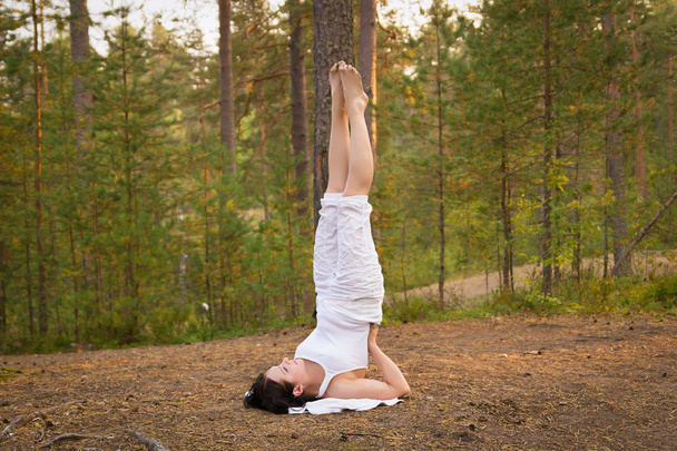 Young woman in Yoga shoulder stand in forest - Photo, image