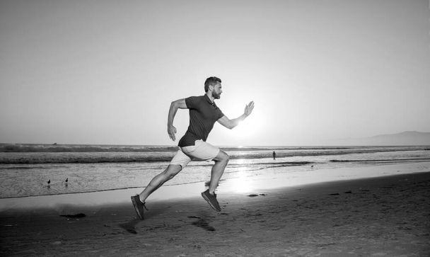urheilija sprinter käynnissä auringonnousun kesärannalla valtamerellä, lenkkeily. - Valokuva, kuva