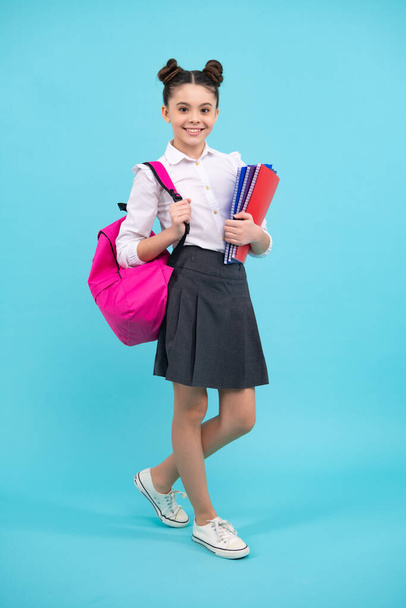 Schoolgirl, teenage student girl hold book on blue isolated studio background. School and education concept. Back to school. Happy teenager, positive and smiling emotions of teen girl - Fotó, kép