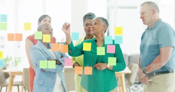 Sticky notes, teamwork and business people working on strategy in office. Collaboration, planning or group of employees with mature female leader writing sales ideas on glass wall in modern workplace. - Footage, Video