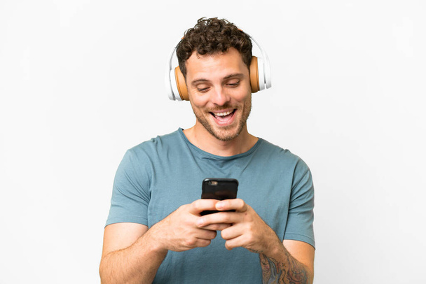joven con auriculares y smartphone sobre fondo gris  - Foto, imagen