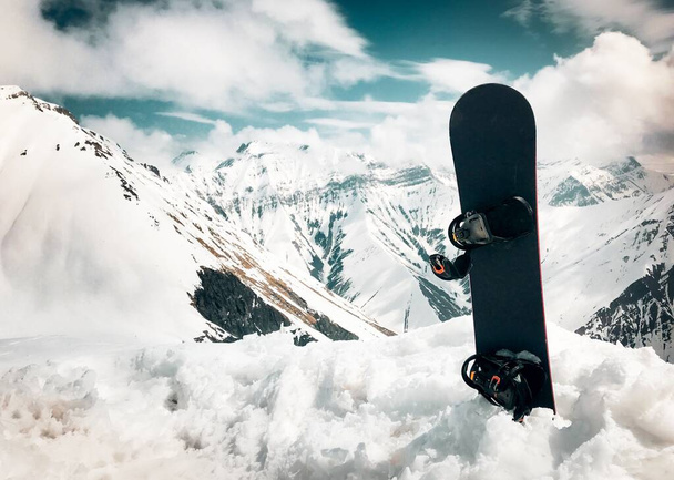Soporte de snowboard en nieve con fondo de hermosas montañas blancas del Cáucaso en el mirador superior de la estación de esquí de Gudauri en invierno. Georgia esquí destino de vacaciones de invierno - Foto, imagen