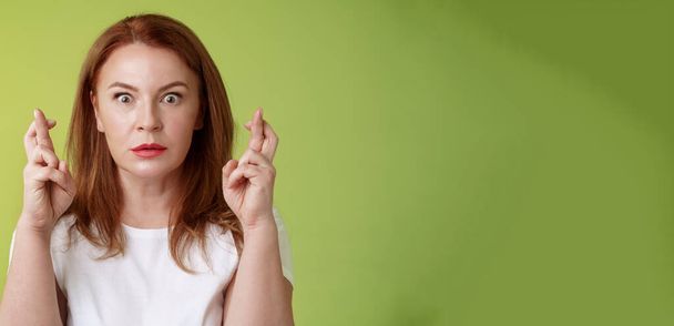 Stunned intense worried middle-aged redhead woman. stare nervously awaiting important result implore dream come true receive positive reply standing stupor green background make wish good luck. - Photo, Image