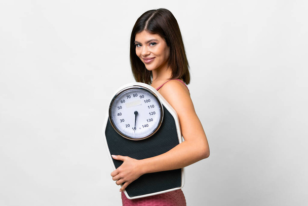 Young Russian woman over isolated white background with weighing machine - Foto, Imagen