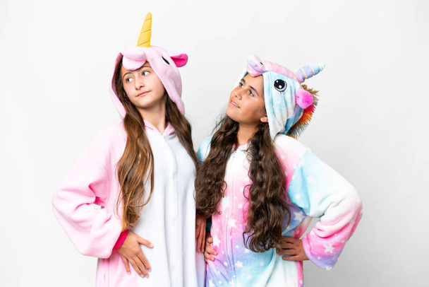 Friends girls with unicorn pajamas over isolated white background posing with arms at hip and laughing - Fotó, kép