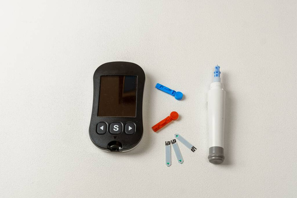 Kit per il trattamento del diabete con misuratore digitale di glucosio nel sangue, lancette, dispositivo di bilanciamento su sfondo bianco - Foto, immagini