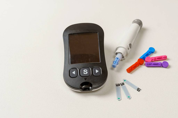 Kit per il trattamento del diabete con misuratore digitale di glucosio nel sangue, lancette, dispositivo di bilanciamento su sfondo bianco - Foto, immagini