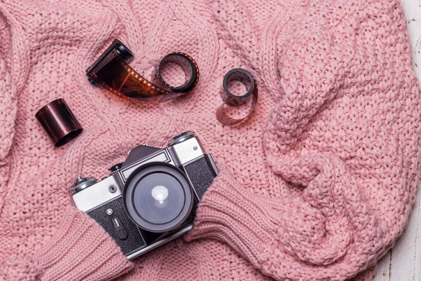 Una vieja cámara retro y película se encuentra en un suéter de lana rosa. Vista desde arriba. - Foto, Imagen