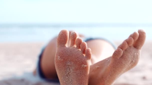 Voeten, zand en ontspannen met een vrouw op het strand, liggend aan zee of oceaan tijdens de zomervakantie. Barefoot, benen gekruist en ontspannen met een vrouwtje aan de kust voor een weekendje weg of vakantie. - Video