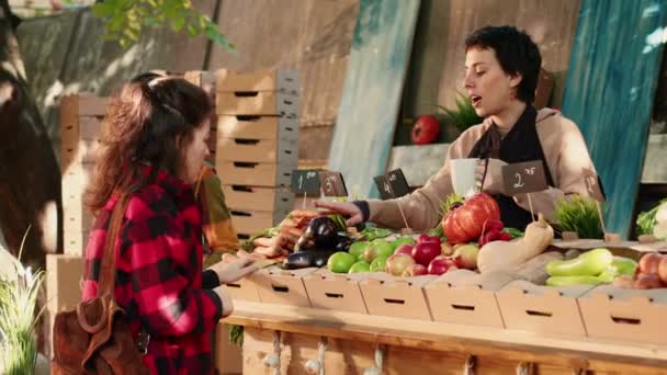 Γυναικεία συνάντηση πωλητή με τον πελάτη στο τοπικό greenmarket για την πώληση νωπών προϊόντων από τον κήπο. Πωλητής και πελάτης αναζητούν βιολογικά εγχώρια φρούτα και λαχανικά, υγιεινά προϊόντα. Σφηνάκι τρίποδα. - Πλάνα, βίντεο