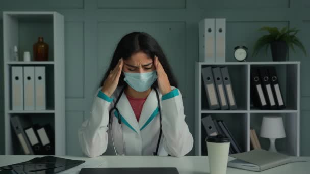Nezdravě unavený nemocný lékař mladá žena v lékařské masce dotek hlavy spánky trpí bolestí hlavy unavený zklamaný žena zdravotní sestra pocit stresu deprese zdravotní problém koronavirus symptom covid-19 - Záběry, video