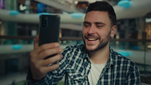 Gülümseyen Arap beyaz erkek blogcu işadamı cep telefonu kamerasına bakıyor alışveriş merkezindeki görüntülü konuşma konuşmasına mutlu genç adam sohbet ediyor çevrimiçi kayıt blogu için modern teknolojiyi uzaktan iletişim için kullanıyor. - Video, Çekim