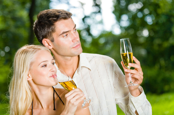 Young happy couple celebrating with champagne outdoors - 写真・画像