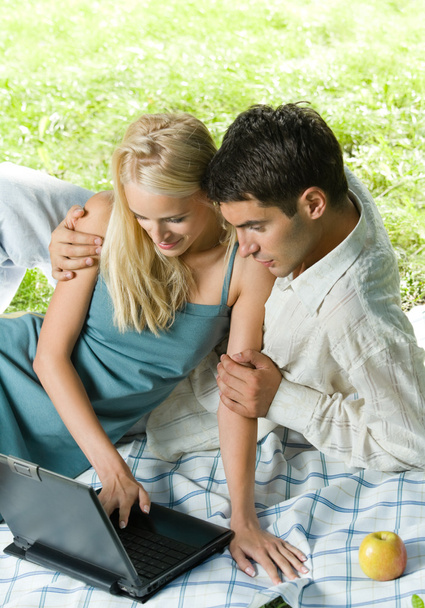 Young happy couple using laptop together, outdoors - 写真・画像