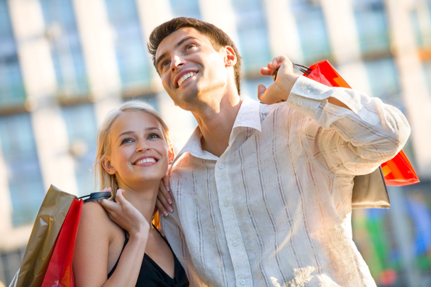 Young attractive happy couple with shopping bags outdoors - Foto, imagen