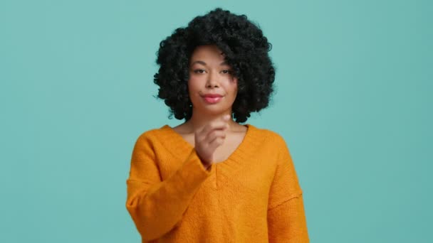 Slow motion studio schoot Afro-Amerikaanse vrouw in fel oranje trui positief glimlachen, kijken in de camera, tonen ritsen, sluiten mond gebaar van stilte, stoppen met praten, willen niet praten - Video