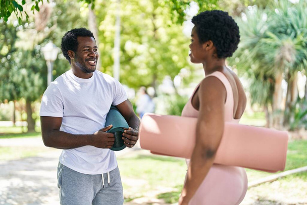 African american man and woman couple holding yoga mat speaking at park - Photo, Image