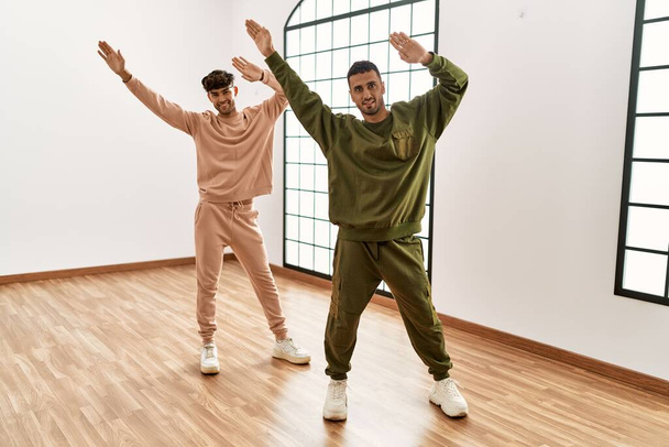 Zwei hispanische Männer Paar Tänzer lächeln selbstbewusst tanzen im Sportzentrum - Foto, Bild