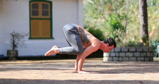 Homem formação Bakasana Yoga asana ao ar livre - Foto, Imagem