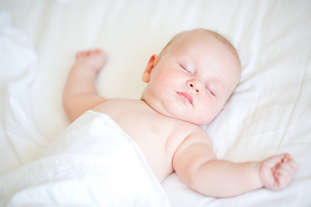 寝ているベッドの上に横たわる穏やかな生まれたばかりの赤ちゃん - 写真・画像