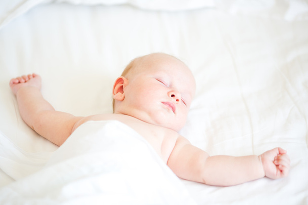寝ているベッドの上に横たわる穏やかな生まれたばかりの赤ちゃん - 写真・画像