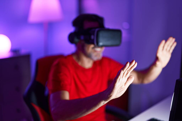 Μεσήλικας άνθρωπος streamer παίζει video game χρησιμοποιώντας γυαλιά εικονικής πραγματικότητας στο gaming room - Φωτογραφία, εικόνα