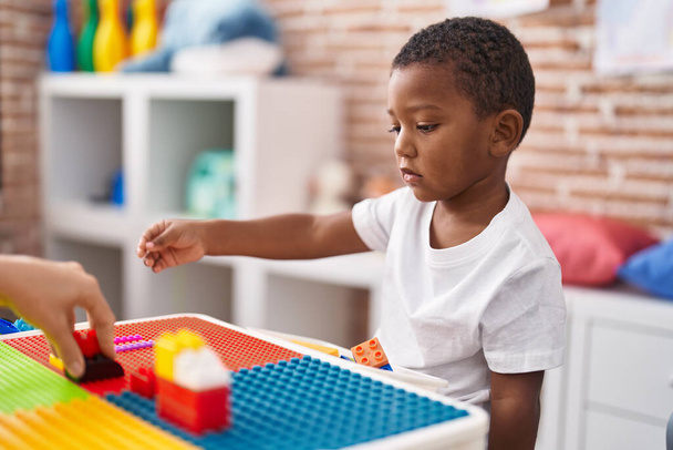 Garçon afro-américain jouant avec des blocs de construction assis sur la table à la maternelle - Photo, image