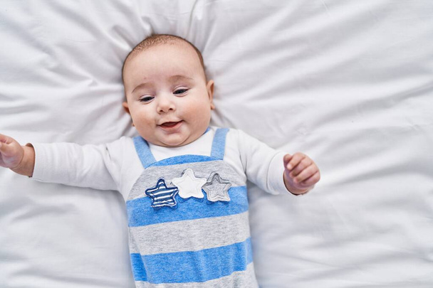 Suloinen vauva hymyilee luottavainen makaa sängyssä makuuhuoneessa - Valokuva, kuva