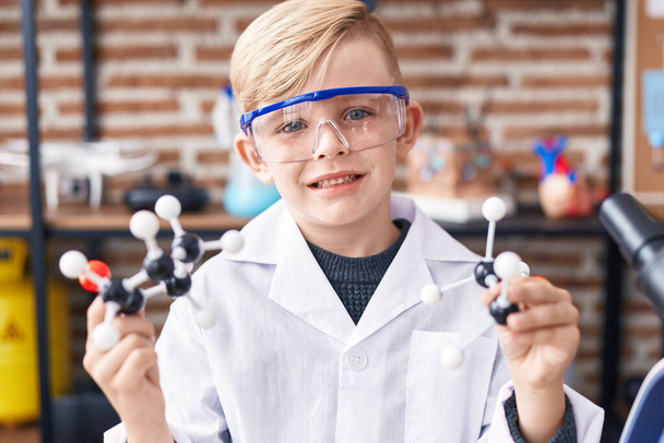 Adorável criança estudante sorrindo confiante segurando molécula na sala de aula - Foto, Imagem