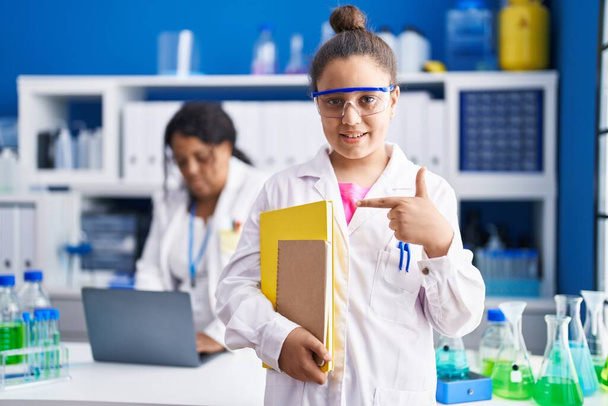 Matka i młoda córka pracują w laboratorium naukowca uśmiechając się szczęśliwie wskazując palcem i ręką  - Zdjęcie, obraz