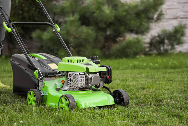 Modern lawn mower on green grass - Photo, Image