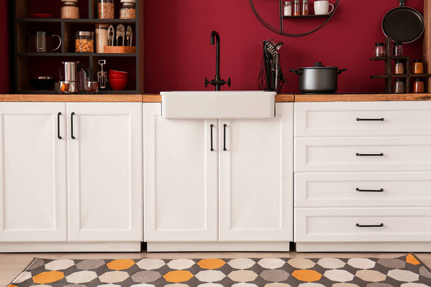 Стильний посуд на прилавках біля кольорової стіни в інтер'єрі кухні
 - Фото, зображення