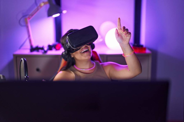 Jeune belle hispanique femme streamer jouer jeu vidéo en utilisant des lunettes de réalité virtuelle à la salle de jeu - Photo, image