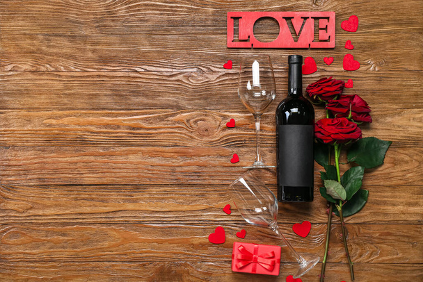 Bir şişe şarap, güller, bardaklar ve aşk kelimesi ahşap arka planda. Sevgililer Günü kutlaması - Fotoğraf, Görsel