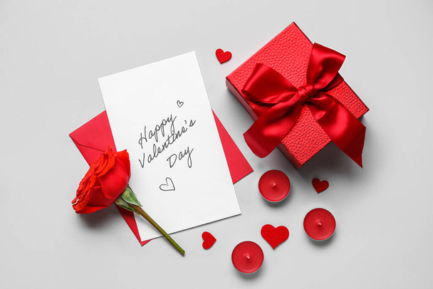 Brief mit Text HAPPY VALENTINE 'S DAY, Rose, Kerzen und Geschenk auf grauem Hintergrund - Foto, Bild