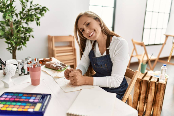 Νεαρή καυκάσια γυναίκα χαμογελά αυτοπεποίθηση κάνουν χειροποίητο πήλινο δοχείο στο στούντιο τέχνης - Φωτογραφία, εικόνα