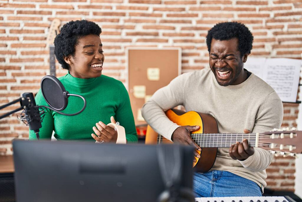 African american man and woman music group singing song playing guitar and tambourine at music studio - Foto, afbeelding