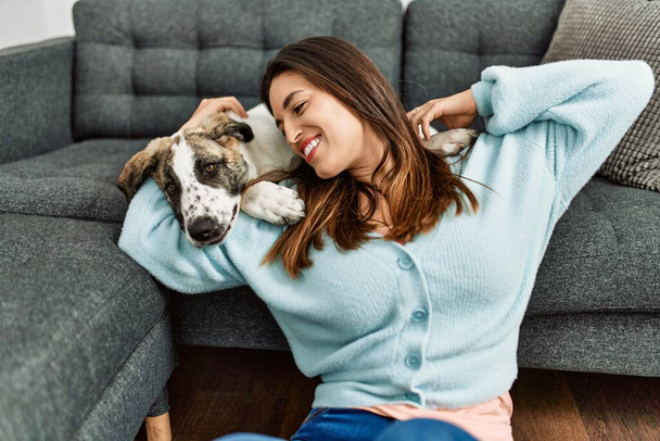 Young woman hugging dog sitting on floor at home - Photo, Image